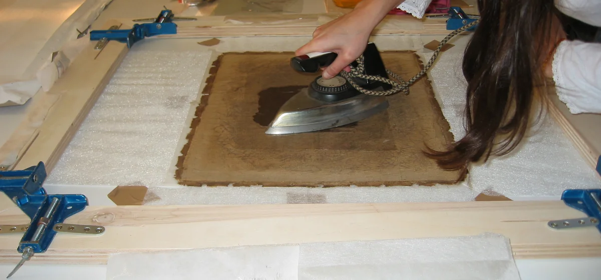 Rentoilage en cours avec fixage à la colle de peau et table chauffante.