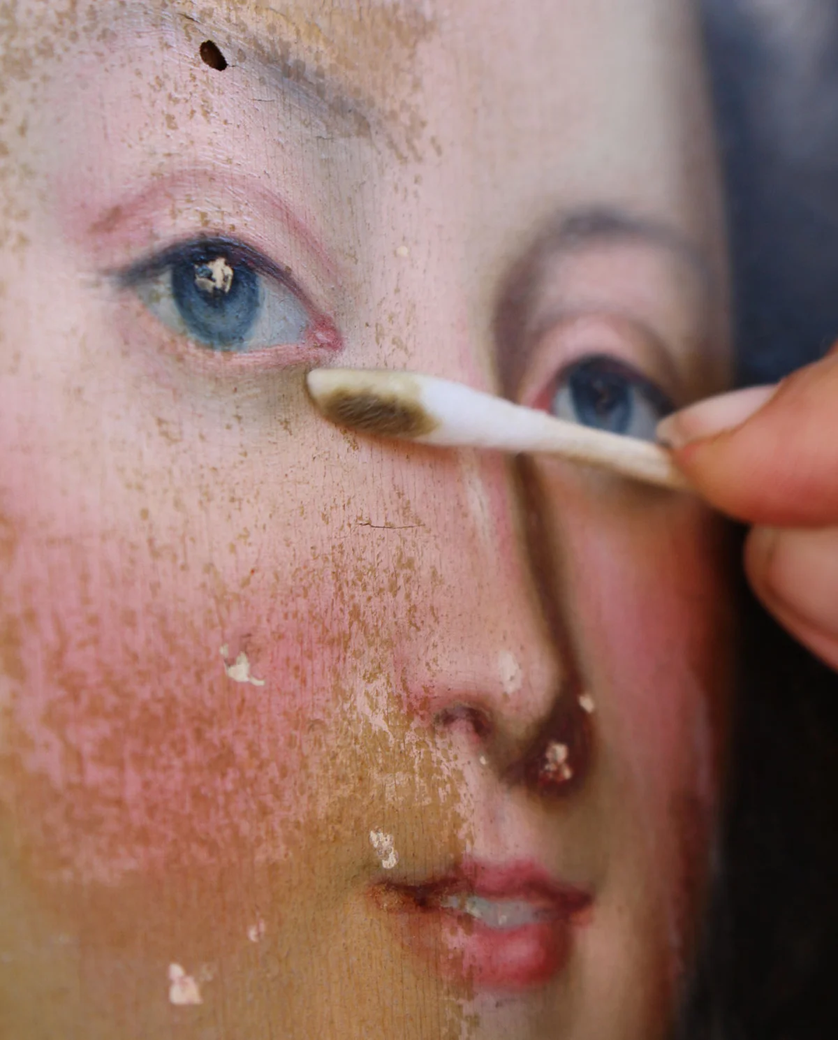 Nettoyage délicat du visage d’un portrait féminin au coton-tige.